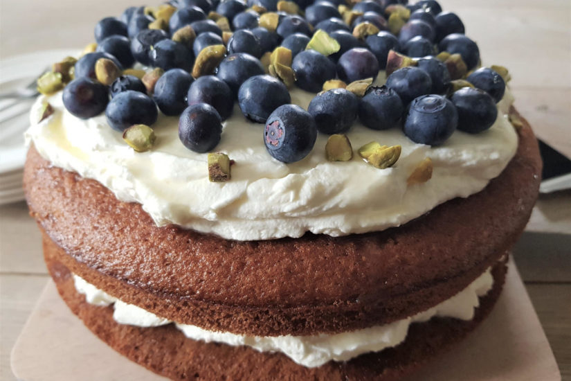 mascarpone taart met sinaasappel, gestapeld en met een topping van blauwe bessen en pistache noten