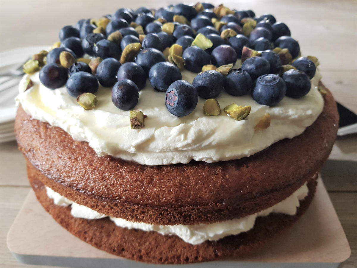 mascarpone taart met sinaasappel, gestapeld en met een topping van blauwe bessen en pistache noten